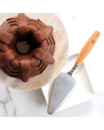 A bundt cake displayed on a plate, accompanied by a cake server on the side.