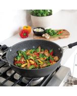 A wok containing a mix of stir-fried vegetables and mushrooms