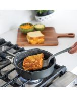 A person prepares a grilled cheese sandwich in a pan, showcasing the bread toasting. 