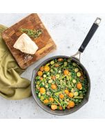A pan filled with vegetables and a slice of cheese on a wooden table.