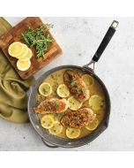 Chicken with lemon and parsley cooking in a skillet pan.