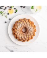 A bundt cake on a white plate, garnished with fresh blueberries and lemon slices for a vibrant presentation.