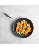Salmon fillets cooking in a skillet, garnished with fresh lemon slices for added flavor.