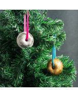 Two shiny metal ornaments hang from a decorated Christmas tree, reflecting light and adding festive charm.