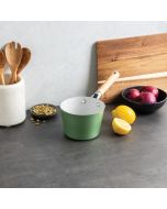 A green saucepan rests on a counter beside a wooden cutting board, creating a cozy kitchen scene.