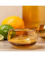 A glass bowl containing a bright orange and a fresh lime, showcasing their vibrant colors and textures.
