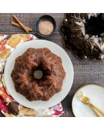 A bundt cake on a plate beside a bowl filled with cinnamon, creating a warm and inviting dessert scene.