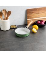 A green pan sits on a counter next to a wooden cutting board and a fresh lemon.