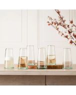 Six clear glass vases arranged on a wooden table, showcasing their transparency and elegant design.
