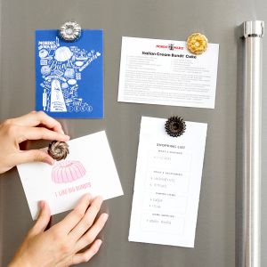 A person is using the refrigerator magnet with a decorative design, emphasizing its bright color and distinctive appearance.
