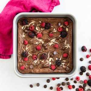  A plate of chocolate brownies topped with fresh raspberries and chocolate chips, showcasing a rich and indulgent dessert.