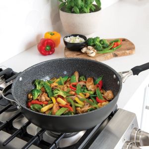 A wok containing a mix of stir-fried vegetables and mushrooms