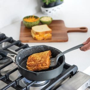 A person prepares a grilled cheese sandwich in a pan, showcasing the bread toasting. 