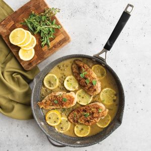 Chicken with lemon and parsley cooking in a skillet pan.