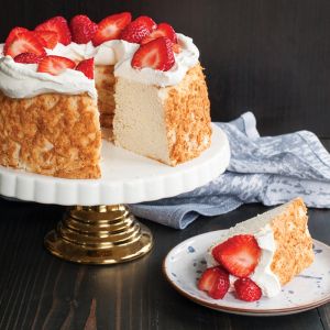 A strawberry cheesecake cake with a slice removed, showcasing its creamy texture and vibrant strawberry topping.