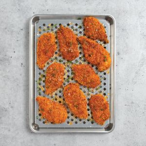 A tray filled with golden-brown chicken nuggets resting on a shiny metal surface.
