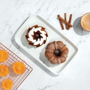 A tray holding two donuts and a steaming cup of coffee, set against a neutral background.