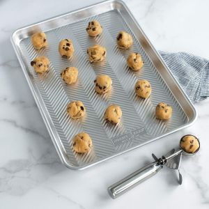 A cookie sheet filled with freshly baked chocolate chip cookies, golden brown and slightly melted chocolate visible.