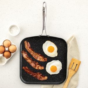 A frying pan containing crispy bacon and sunny-side-up eggs, ready to be served for breakfast.