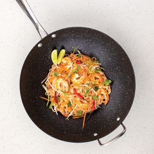 A skillet filled with sautéed vegetables and meat, resting on a stovetop, with steam rising from the food.