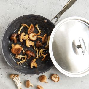 A covered pan containing fresh mushrooms, showcasing a simple cooking setup in a kitchen environment.