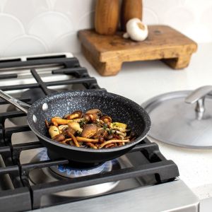  A pan filled with food sits on a stove, with flames visible beneath it, indicating cooking in progress.