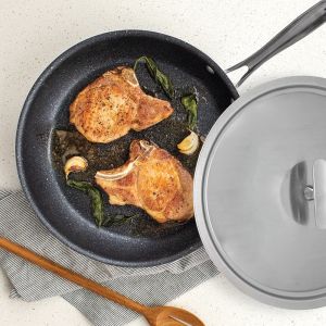 A frying pan containing two pieces of meat, sizzling and cooked to a golden brown.