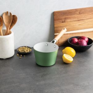 A green saucepan rests on a counter beside a wooden cutting board, creating a cozy kitchen scene.