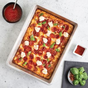 A square pan filled with pepperoni and melted cheese, showcasing a delicious pizza ready to be served.