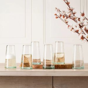 Six clear glass vases arranged on a wooden table, showcasing their transparency and elegant design.
