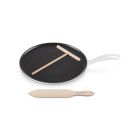 Le Creuset 10.25" Traditional Round Crepe Pan against a white background, shot slightly from above. The t-shaped rake is set atop the pan, and the thin spatula is placed in front of the pan.  Image