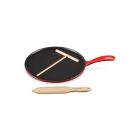 Le Creuset 10.25" Traditional Round Crepe Pan against a white background, shot slightly from above. The t-shaped rake is set atop the pan, and the thin spatula is placed in front of the pan.  Image