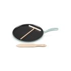 Le Creuset 10.25" Traditional Round Crepe Pan against a white background, shot slightly from above. The t-shaped rake is set atop the pan, and the thin spatula is placed in front of the pan.  Image