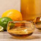 A glass bowl containing a bright orange and a fresh lime, showcasing their vibrant colors and textures.
 Image