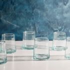 Six empty glass tumblers arranged neatly on a wooden table, reflecting light in a bright setting. Image