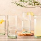 Four glasses filled with water and garnished with lemon slices, arranged on a table. Image