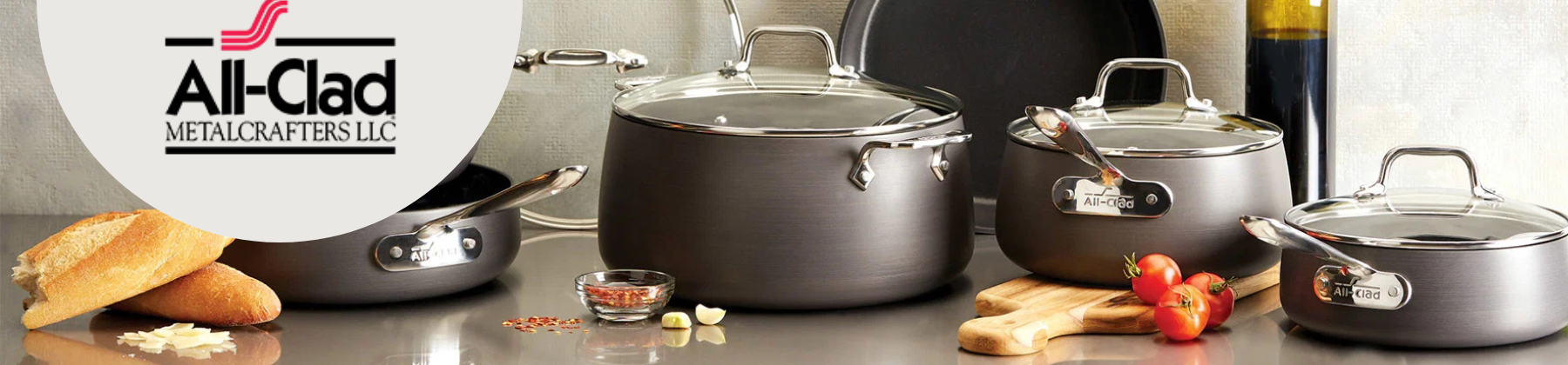 Photo of All-Clad Cookware set surrounded by bread and tomatoes.