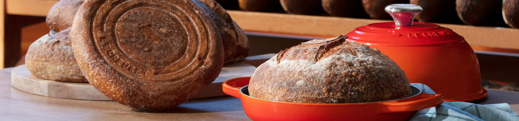 Photo of Le Creuset bread oven on table with bread.